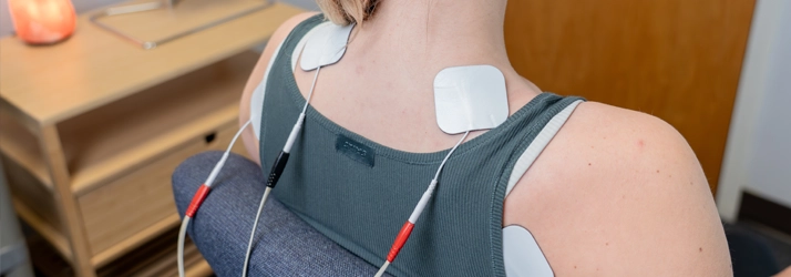 Woman with gray tank top and e-stim stickers on her back