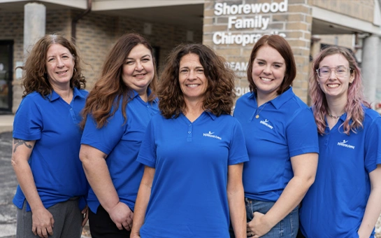 A group of five individuals wearing matching blue collared shirts stands outdoors