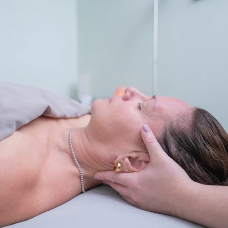 A person is lying on a therapy table with a light-colored towel