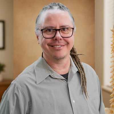 A person in a gray button up shirt with long, partially braided hair pulled back