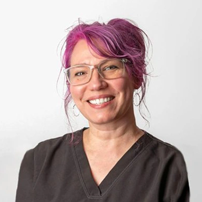 A person with bright pink hair styled in a loose updo is shown from the shoulders up