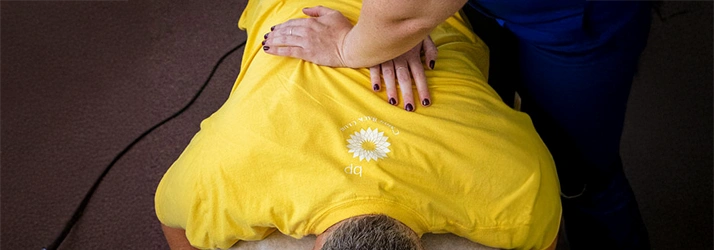 A person wearing a yellow shirt lies face‑down on a padded surface