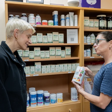 Two individuals stand inside a supplement display area